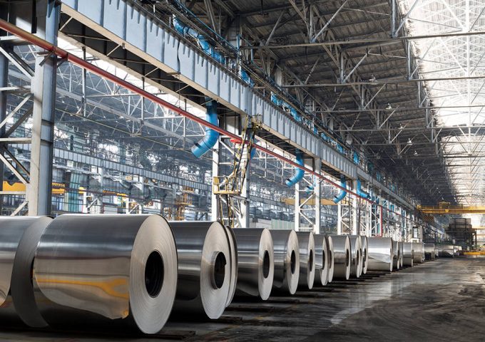 Long row of rolls of aluminum in production shop of plant.